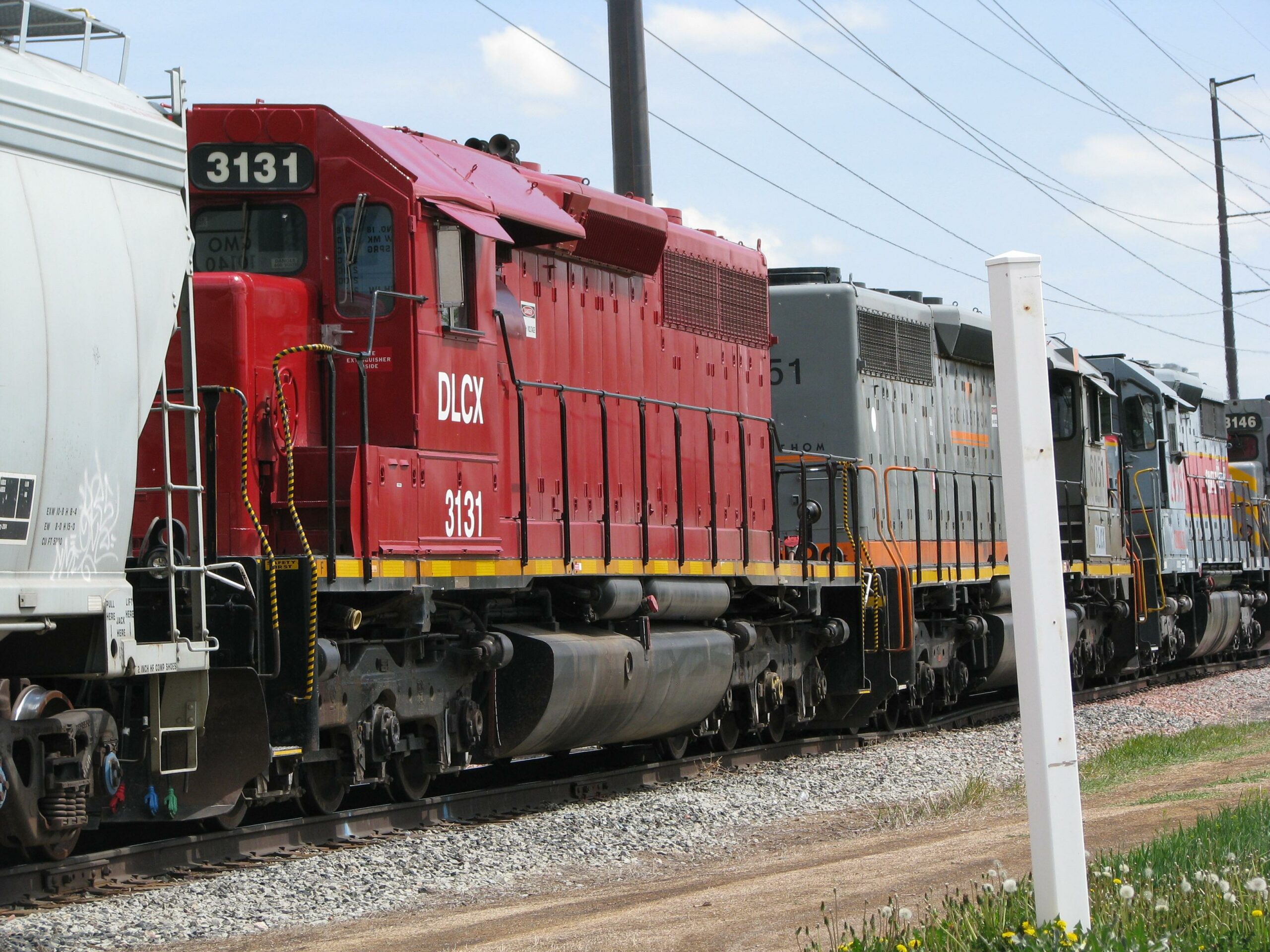 A Red and Black Locomotive Labeled DLCX 3131 is Connected to Two Other Locomotives on a Railway Track